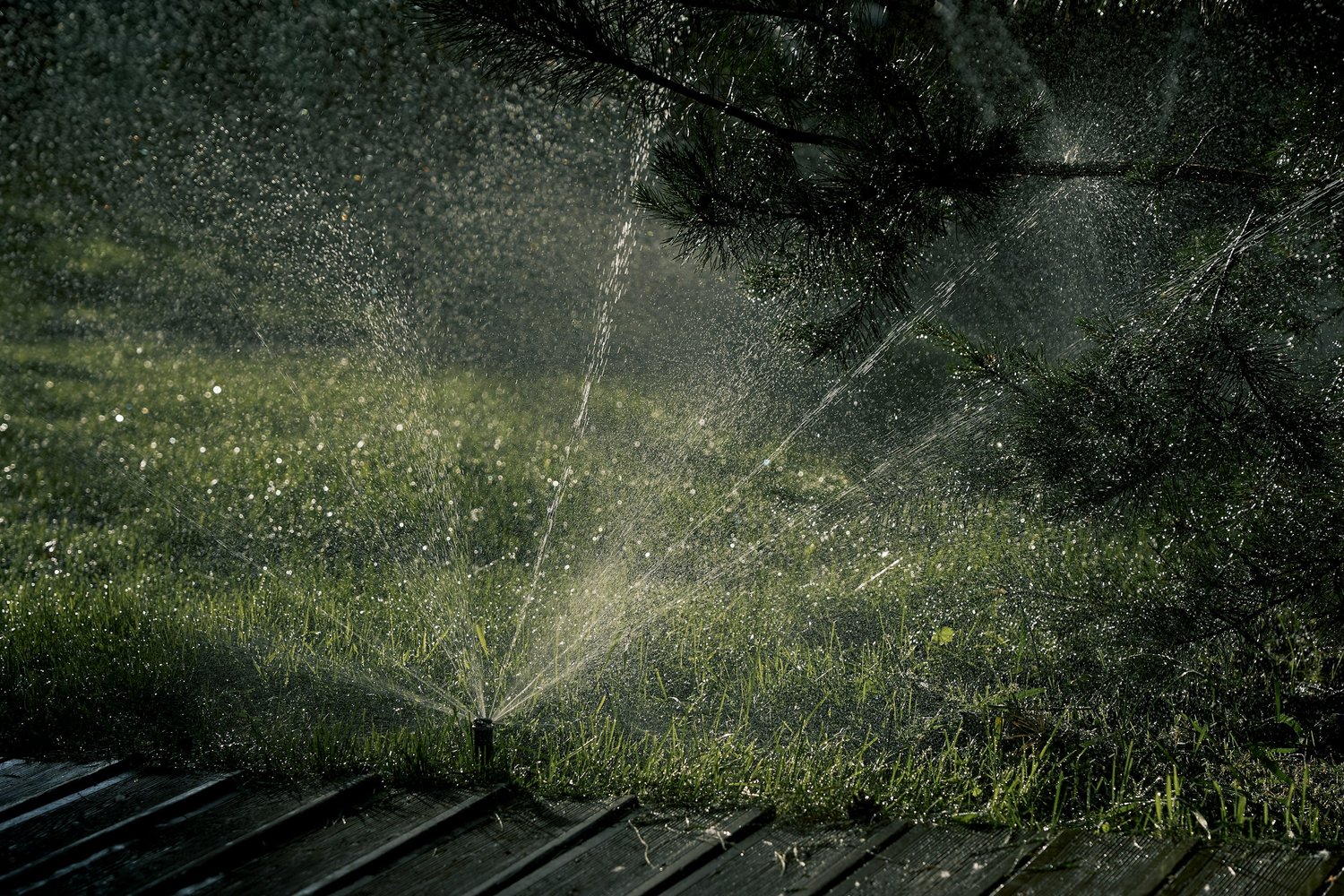 Professional lawn sprinkler system in action, creating a beautiful water pattern over a lush green lawn